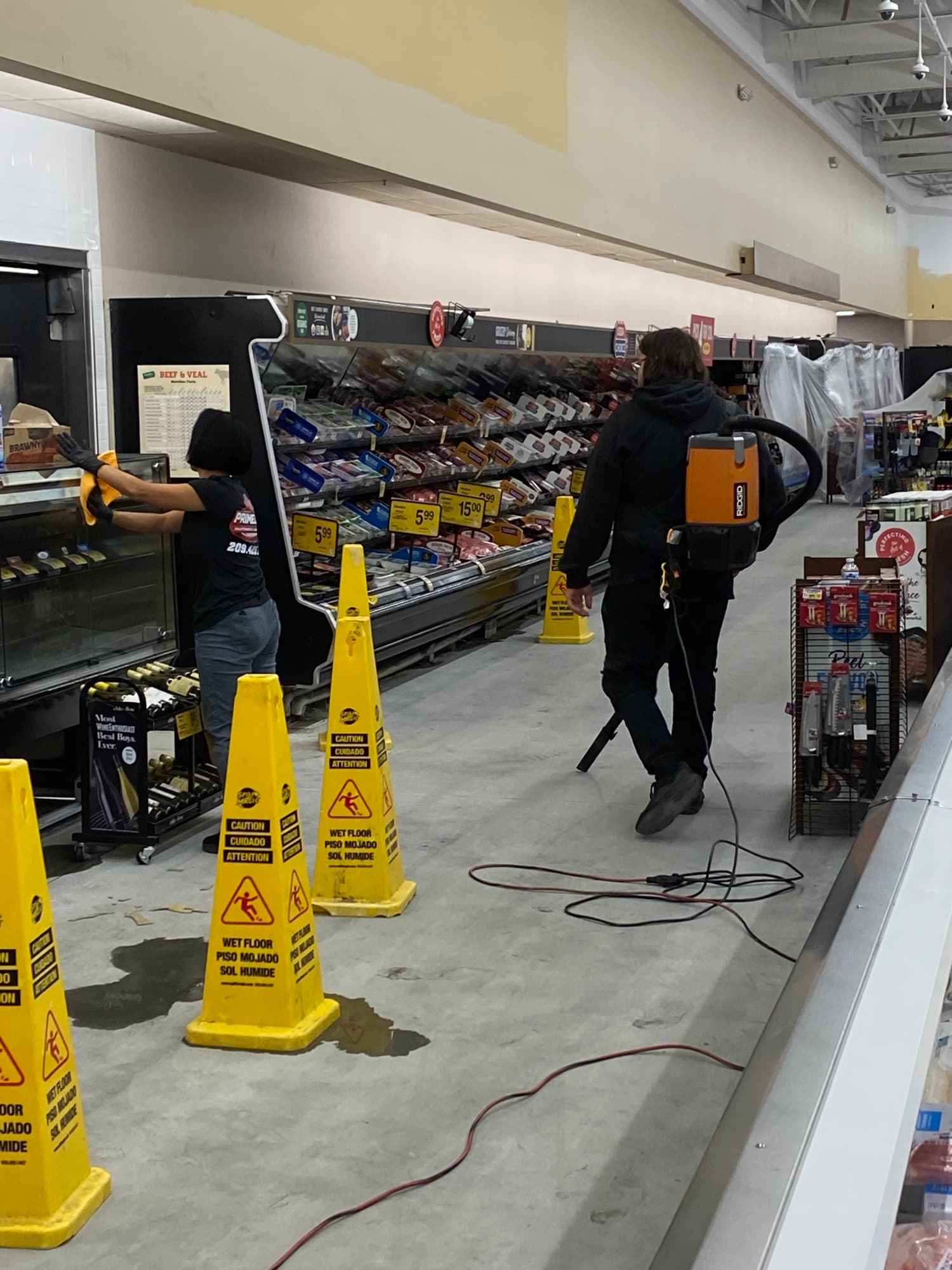 Two Primeline Maintenance & Janitorial crew members cleaning a grocery store meat department